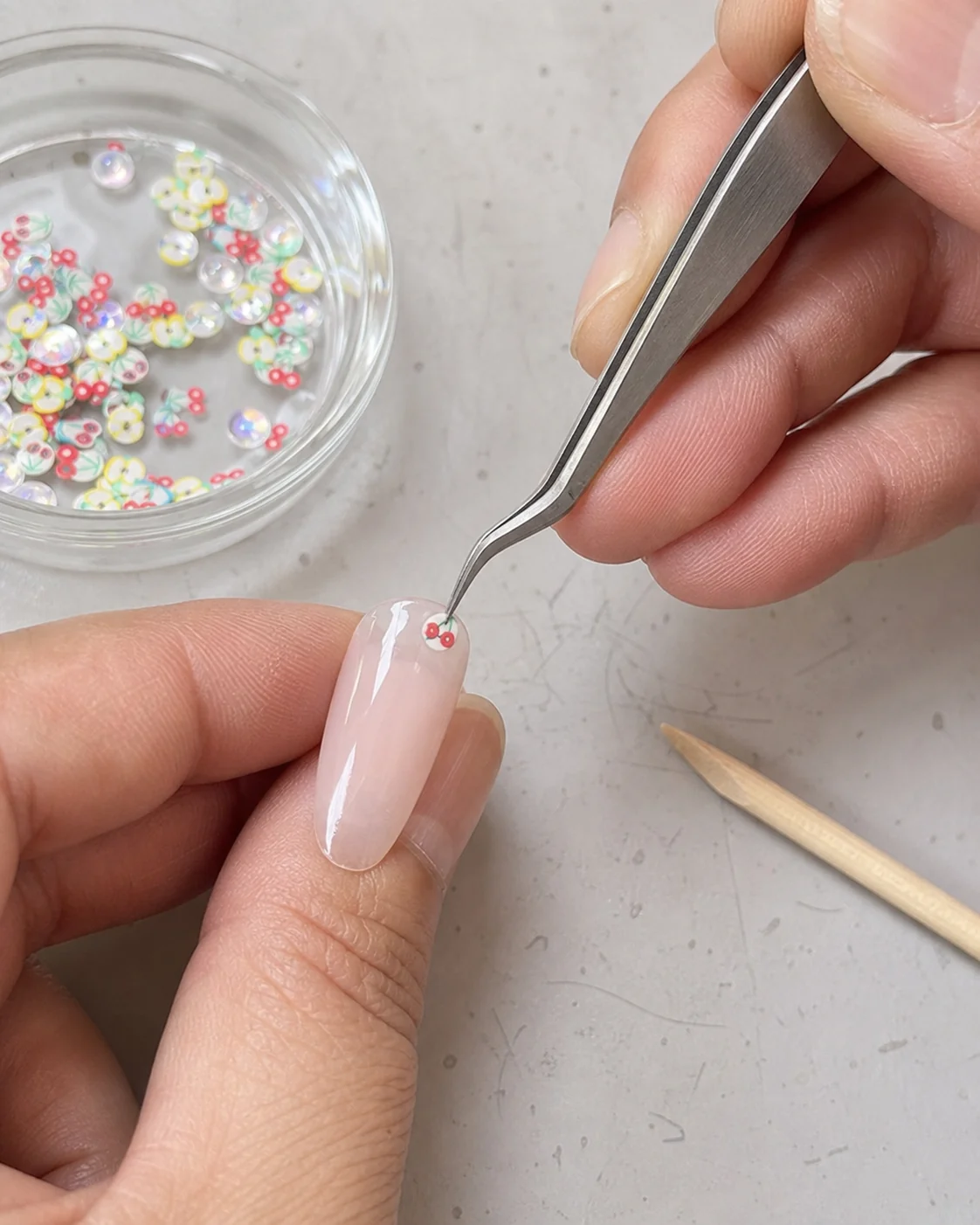 Close application view of miniature fruit slices and glitter used for nail decoration concepts