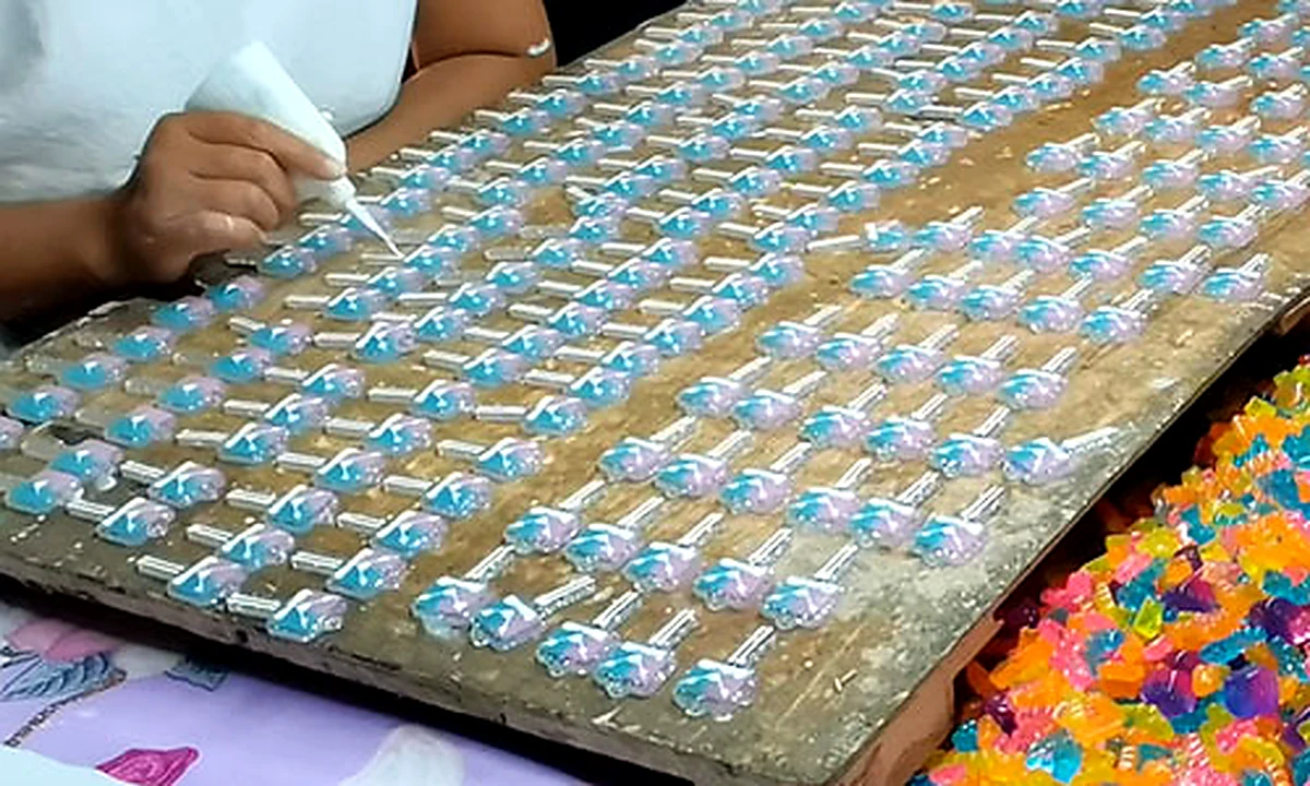 Worker applying paint or UV coating to small craft components